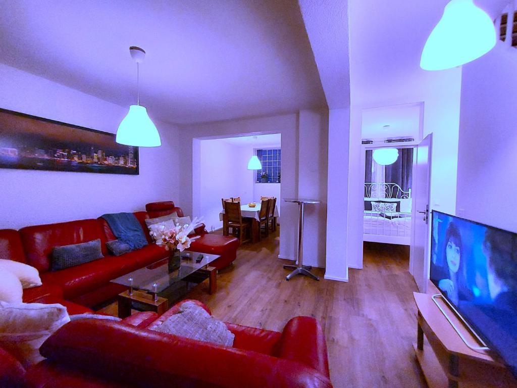 a living room with red couches and a television at Apartmenthaus Schlosspark in Worms
