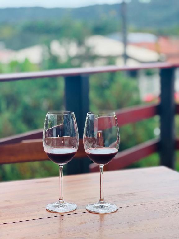 two glasses of red wine sitting on a wooden table at Recanto Porto Chalé e SPA in Penha