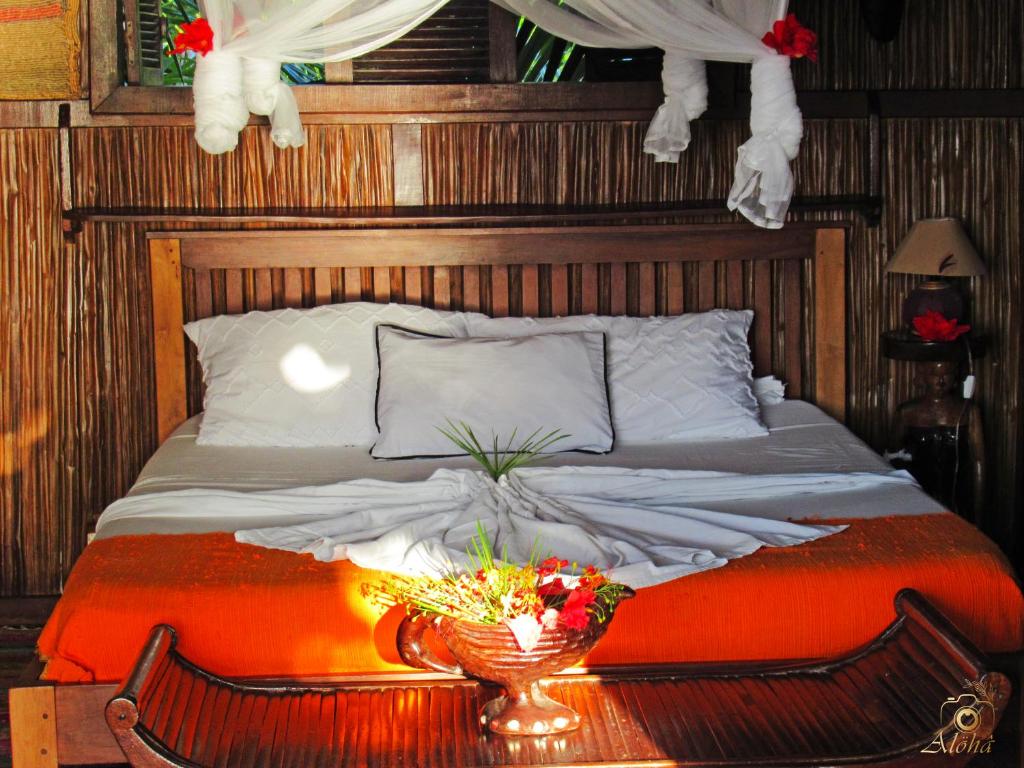 a bed with a table with a bowl of flowers on it at Analatsara Eco Lodge in Ile aux Nattes