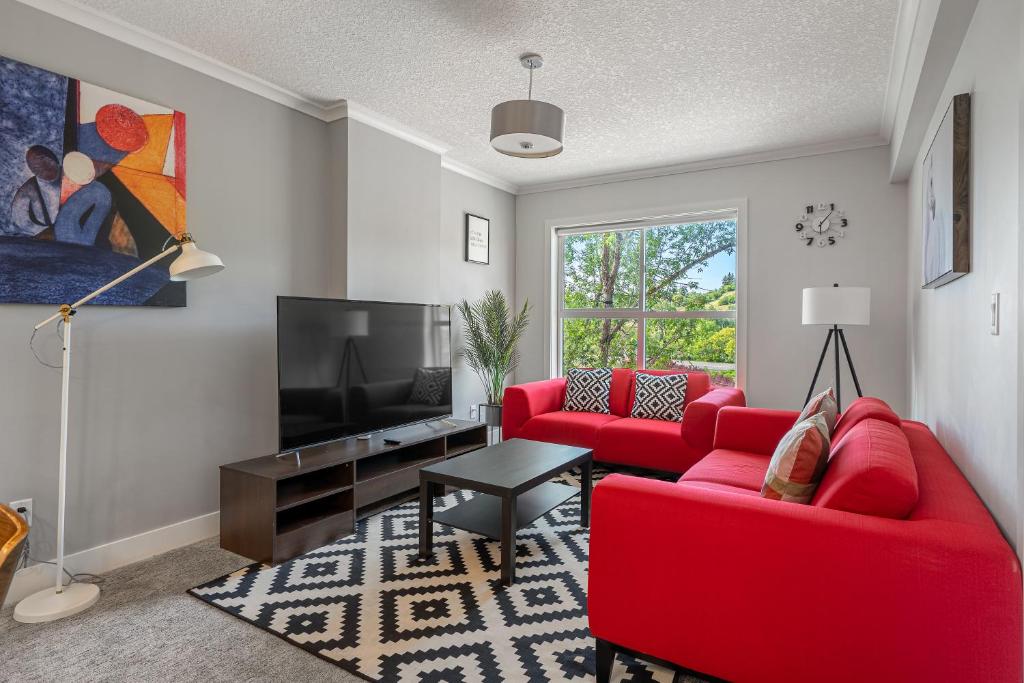 a living room with red furniture and a flat screen tv at Vibrant Stylish, Cozy Waterfront Downtown in Calgary