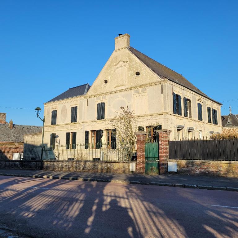 an old white building with a fence on a street at Vallee du Ton in Origny-en-Thiérache