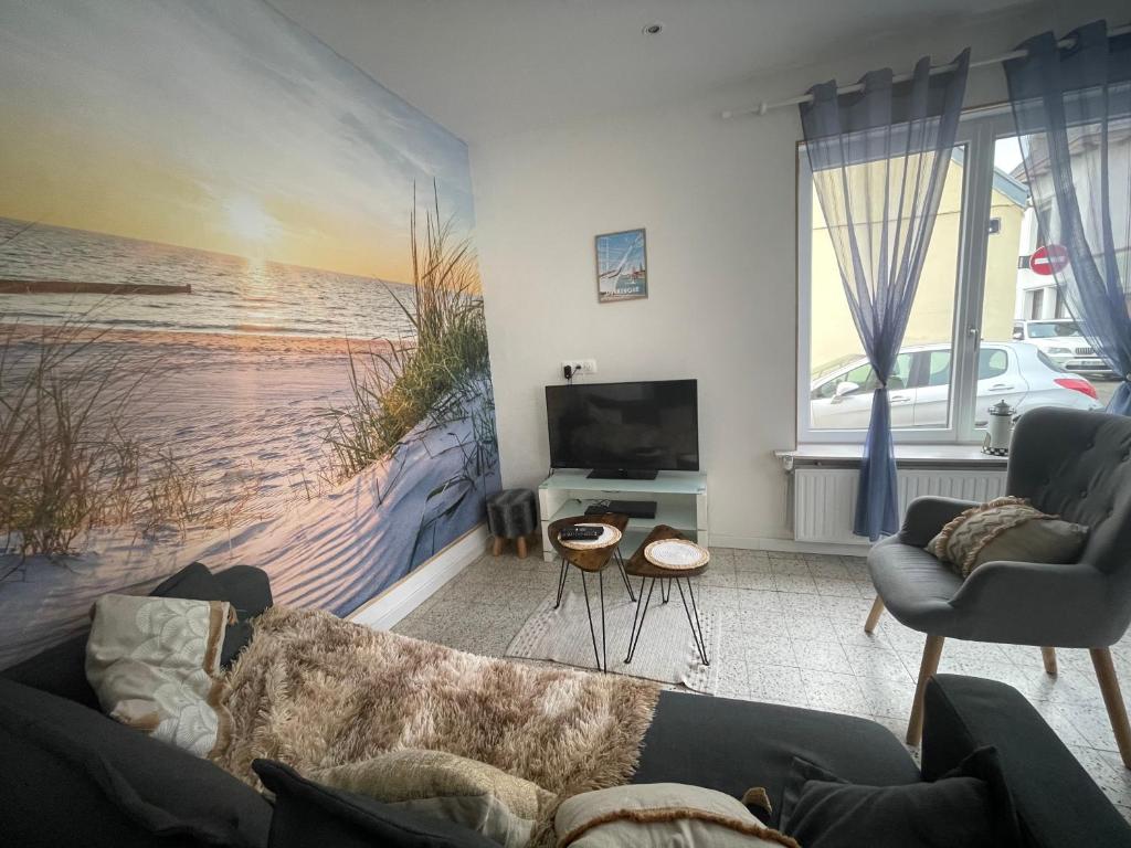 a living room with a couch and a painting of a beach at Au gîte des Frangines in Grand-Fort-Philippe
