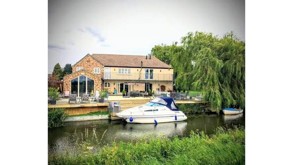 a boat in the water in front of a house at Riverside Lodge Self-Catering Apartment in Peterborough