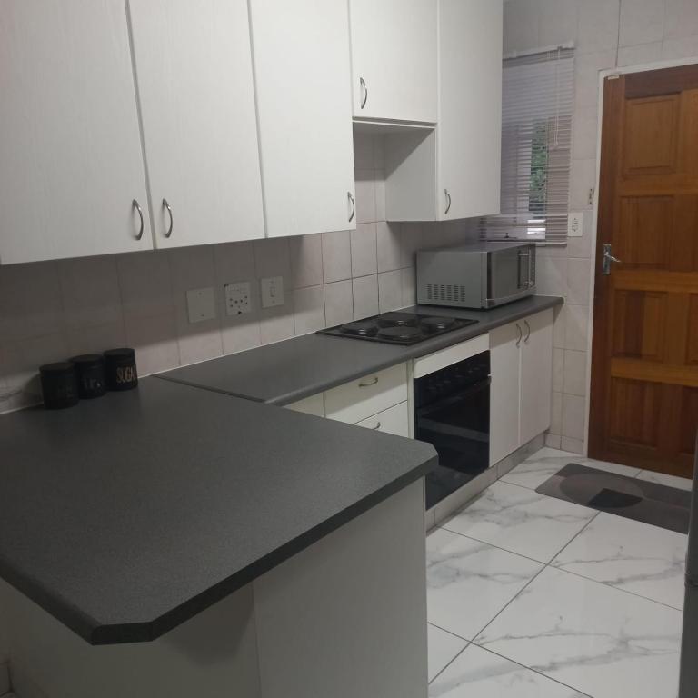a kitchen with white cabinets and a black counter top at Comfort Retreat in Roodepoort