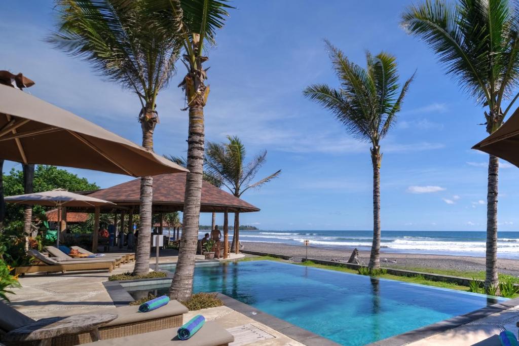 a swimming pool with palm trees and the beach at WIDE SANDS Beach Retreat in Pulukan