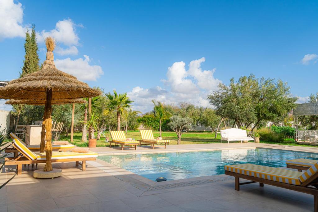 a swimming pool with lounge chairs and an umbrella at Maison soli Marrakech in Bou Khaoua