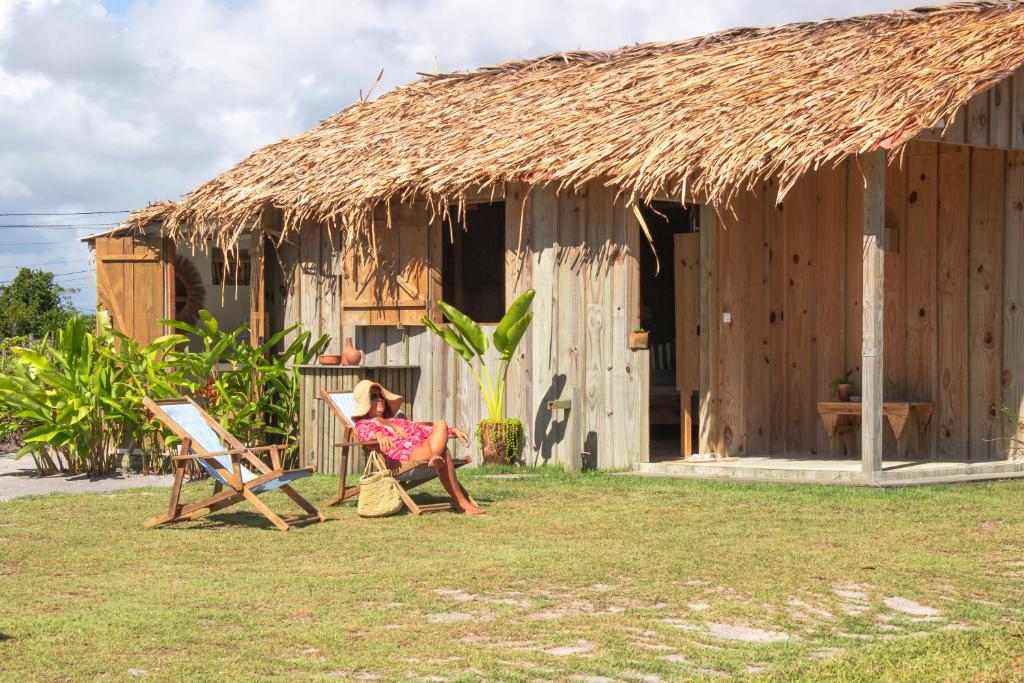 a woman sitting in a chair in front of a hut at Cabana Cachandó in Corumbau