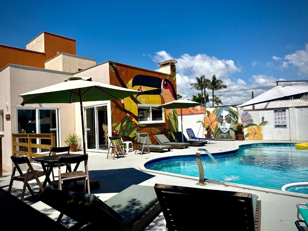 a swimming pool with chairs and umbrellas next to a building at Pousada Pássaros Park in Itapoa