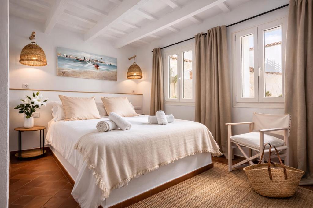 a white bedroom with a bed and a chair at Hotel Boutique Ses Penyes in Alaior