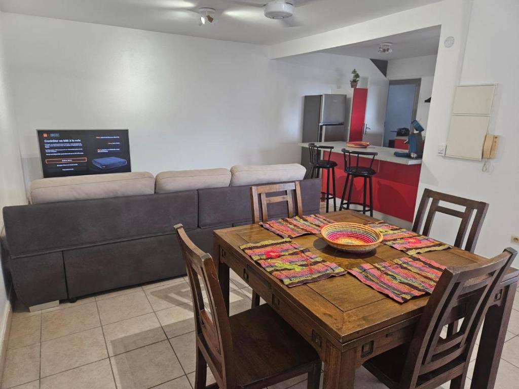 a dining room with a table and a couch at Le paille en queue in Saint-Pierre