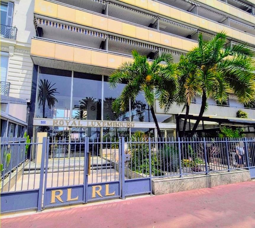 a building with palm trees in front of a fence at Royal Luxembourg Nice Prom' in Nice