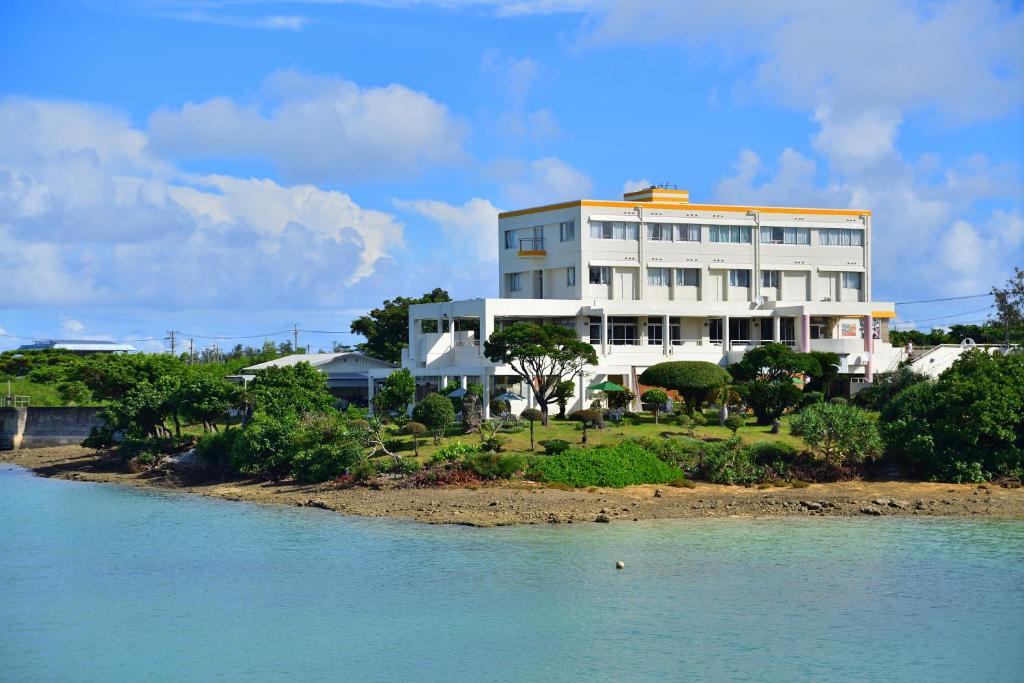 a large white house sitting in front of a body of water at Hotel South Island in Miyako-jima