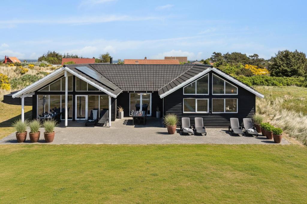 a black house with lounge chairs in front of it at Feriehus 1130 in Hvide Sande