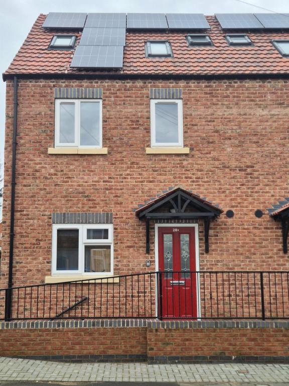 a brick house with a red door and solar panels at Brigg new build home in Brigg
