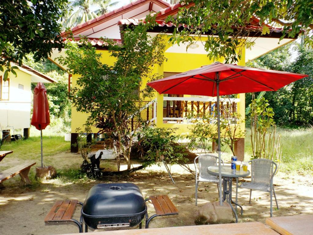 a patio with a table and a grill and a red umbrella at Mango House in Lamai