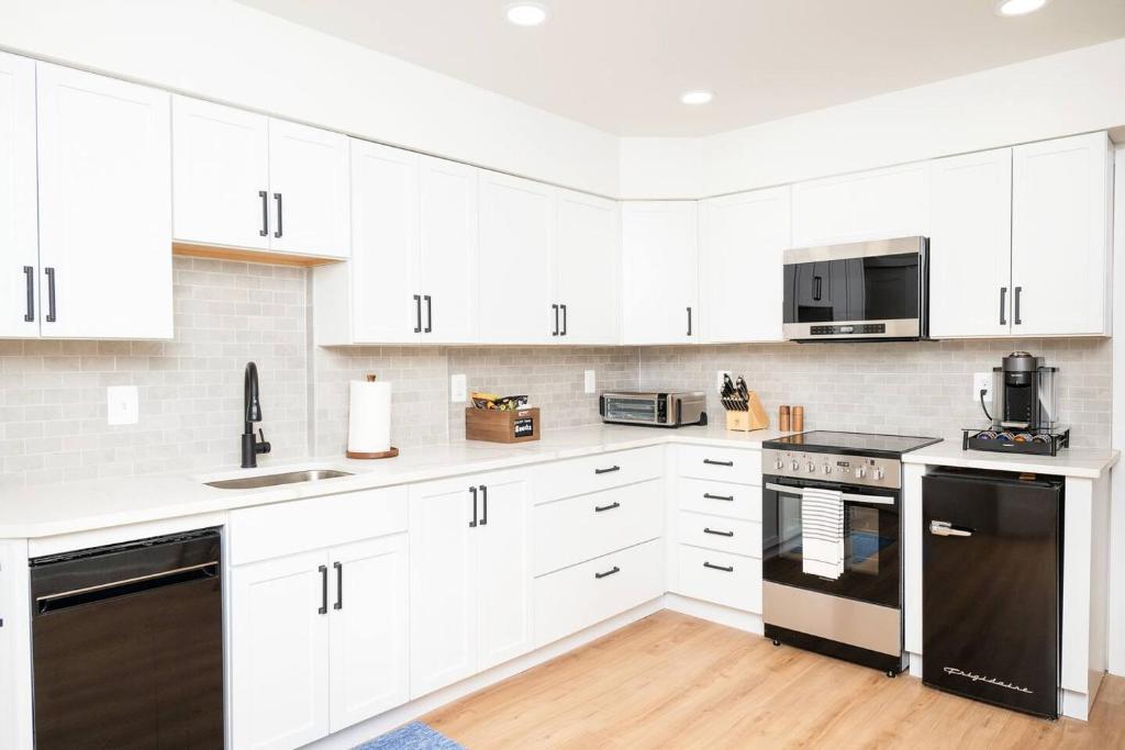 a white kitchen with white cabinets and black appliances at Pint-Sized on Poplar in Cambridge