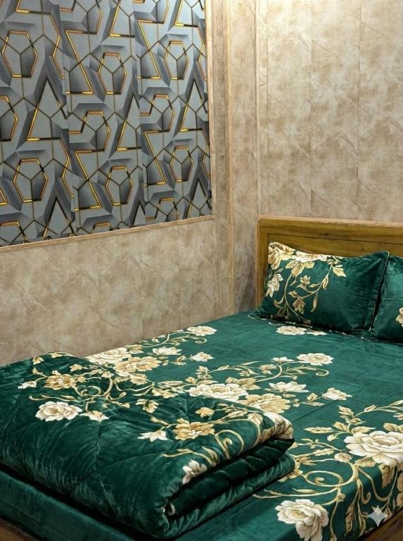 a bedroom with a bed with a green comforter at Hotel Al Mehraj in Mumbai