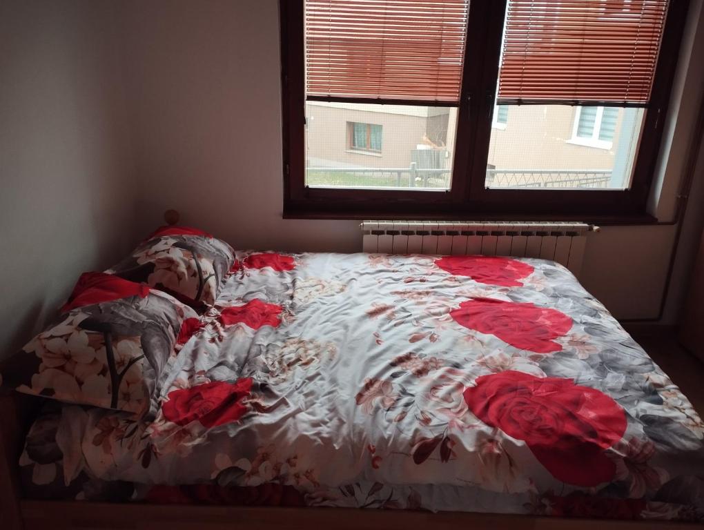a bed with a floral comforter and a window at Apartmani Emir in Visoko