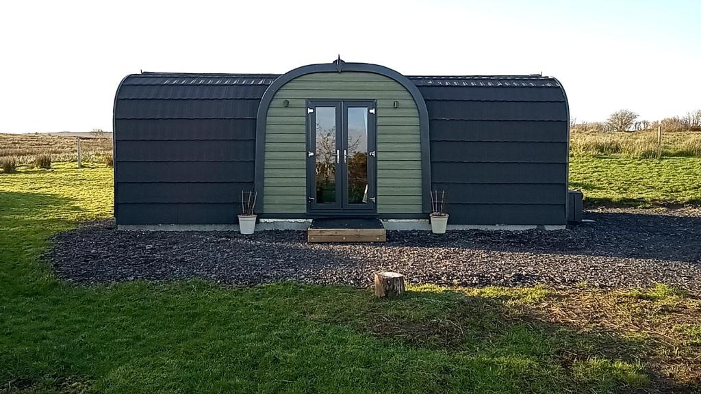 a green building with a door in a field at Foxwell in Ballina