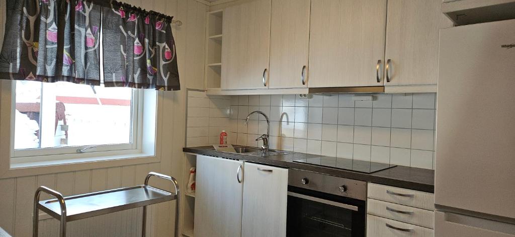 a kitchen with white cabinets and a sink and a window at Håkon Gjestehus in Olderdalen