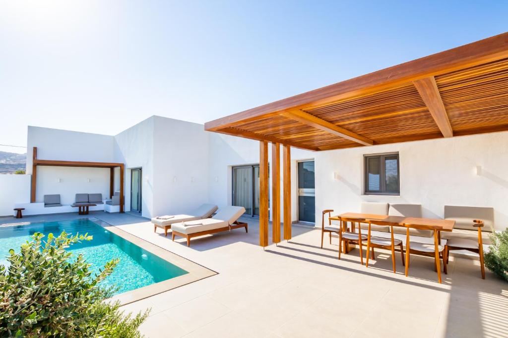 a villa with a swimming pool and a dining area at Manos Villas in Karpathos