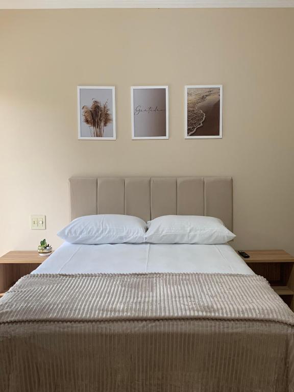 a bedroom with a bed with four pictures on the wall at Suíte de Casal Privativa com Sacada in Sao Jose do Rio Preto