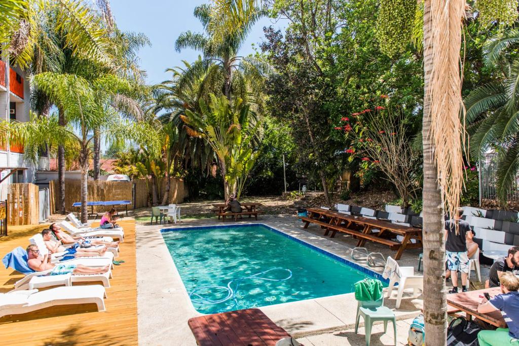 un grupo de personas sentadas alrededor de una piscina en Billabong Backpackers Resort, en Perth