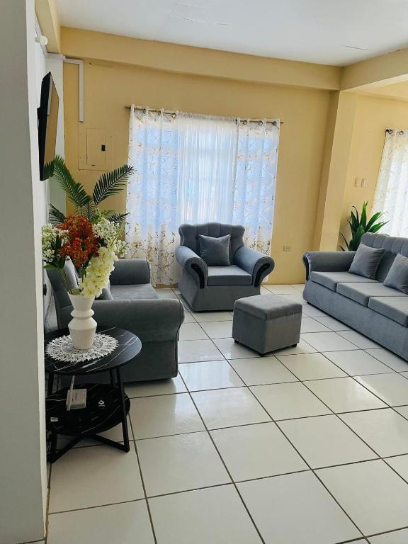a living room with two couches and a table at Lyn Tropical Getaway in Port-of-Spain
