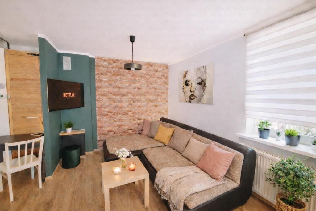 a living room with a couch and a brick wall at Dom Przyjaźni in Kędzierzyn-Koźle