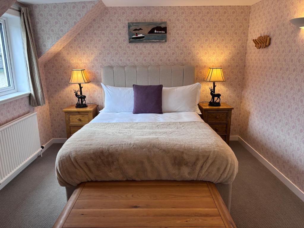 a bedroom with a large bed with two lamps at The Ullapool Rooms in Ullapool
