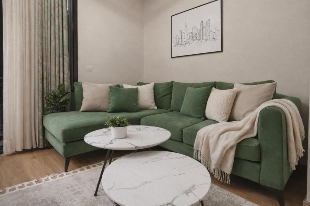 a living room with a green couch and a table at Red School Central Apartment New Bazaar in Tirana