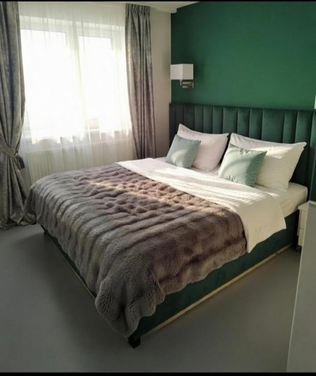 a bedroom with a large bed with a green wall at Apartamenty PETRA Supraśl in Supraśl