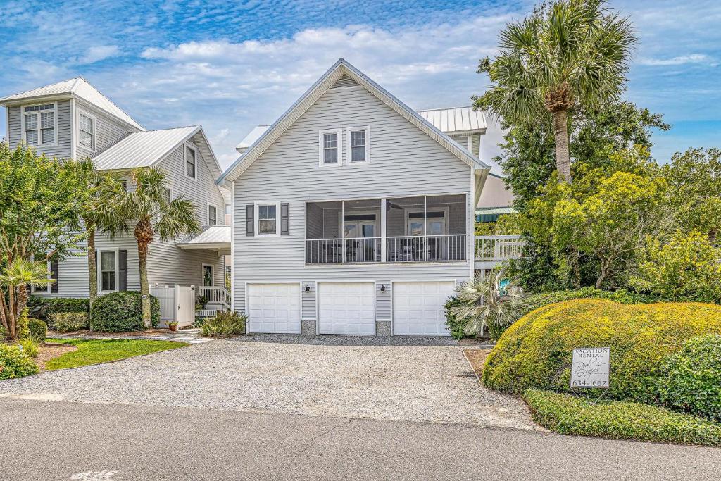 a white house with a garage and palm trees at 221 Olive Way in Saint Simons Island