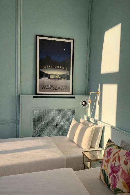 a bedroom with two beds and a picture on the wall at 4th Floor Bed and Breakfast in Warsaw