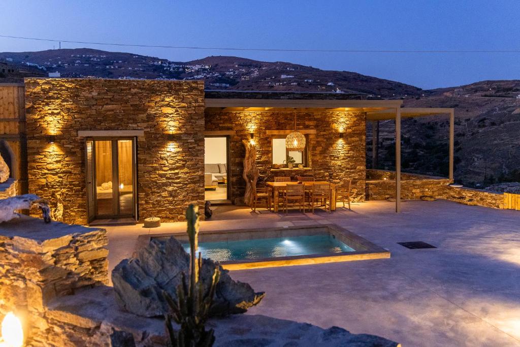 a stone house with a swimming pool at night at Marilias cycladic home in Agios Fokas
