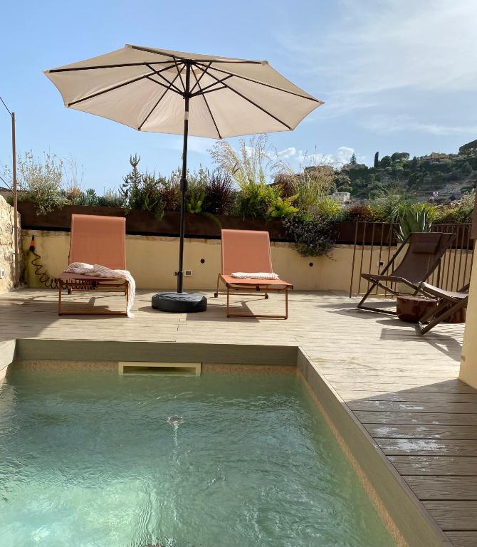 two chairs and an umbrella next to a swimming pool at Tantillo Cinque in Modica