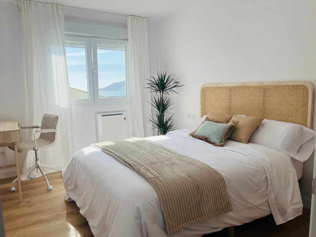 a white bedroom with a large bed with a window at RÍA LIVING - Calma 02 in Cee