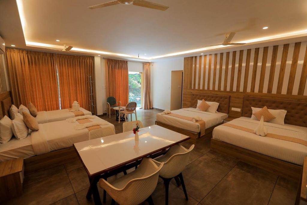 a hotel room with two beds and a table at By the stream resort wayanad in Padinjarathara