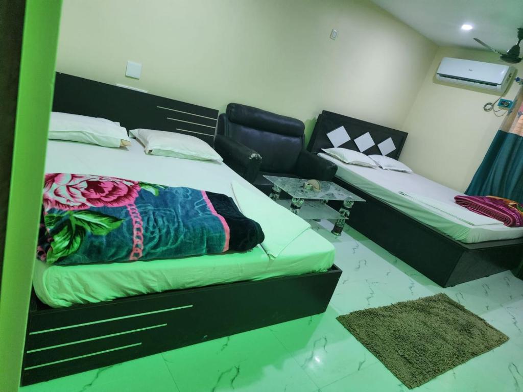 a bedroom with two beds and a couch and a table at Paromita inn in Tajpur