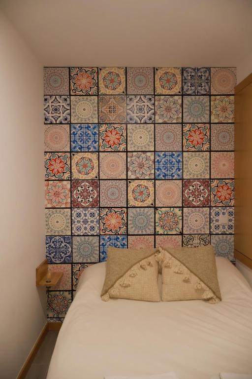 a room with a bed with a wall with tiles at VIELA Guest House T1 in Barcelos