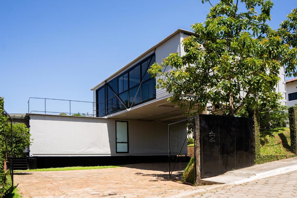 a house with glass windows and a tree at Casa Container Moderna com Vista da Natureza em Itajaí in Itajaí