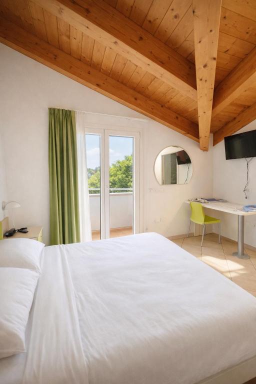 ein Schlafzimmer mit einem großen weißen Bett und einem Schreibtisch in der Unterkunft Hotel Sasselli Dipendenza Hotel Zamagna in Cesenatico