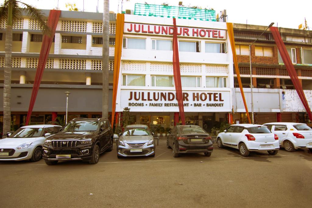 a parking lot with cars parked in front of a building at Jullundur Hotel & Restaurant in Chandīgarh