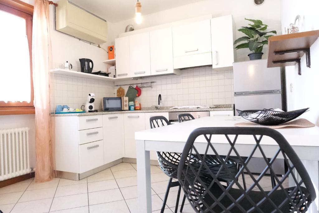 a white kitchen with white cabinets and black chairs at Casa Segantini - Relax Apartment 2 in Arco