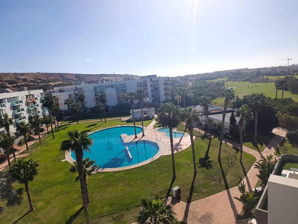 an image of a swimming pool in a park with palm trees at ALMERIMAR GOLF AND PoOL APARTMENT in Almerimar