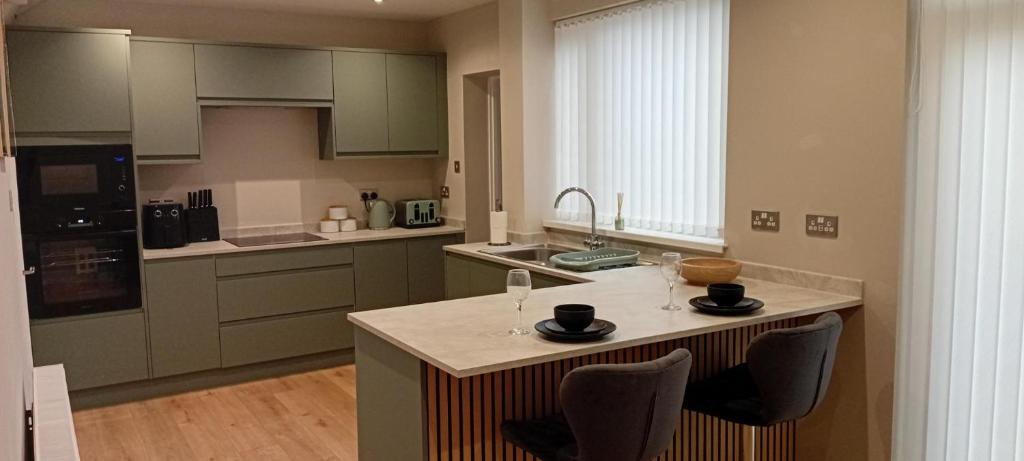 a kitchen with a island with two wine glasses on it at Martindale Close - 3 Bedrooms - Sleeps 5 in Whitehaven