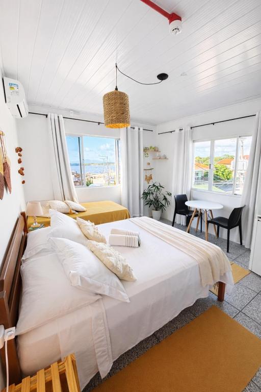 a bedroom with a large white bed and a table at Pousada Surf na Guarda in Guarda do Embaú