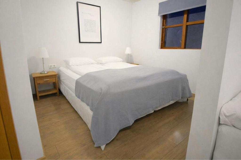 biała sypialnia z łóżkiem i oknem w obiekcie Malarhorn Accommodations w mieście Drangsnes