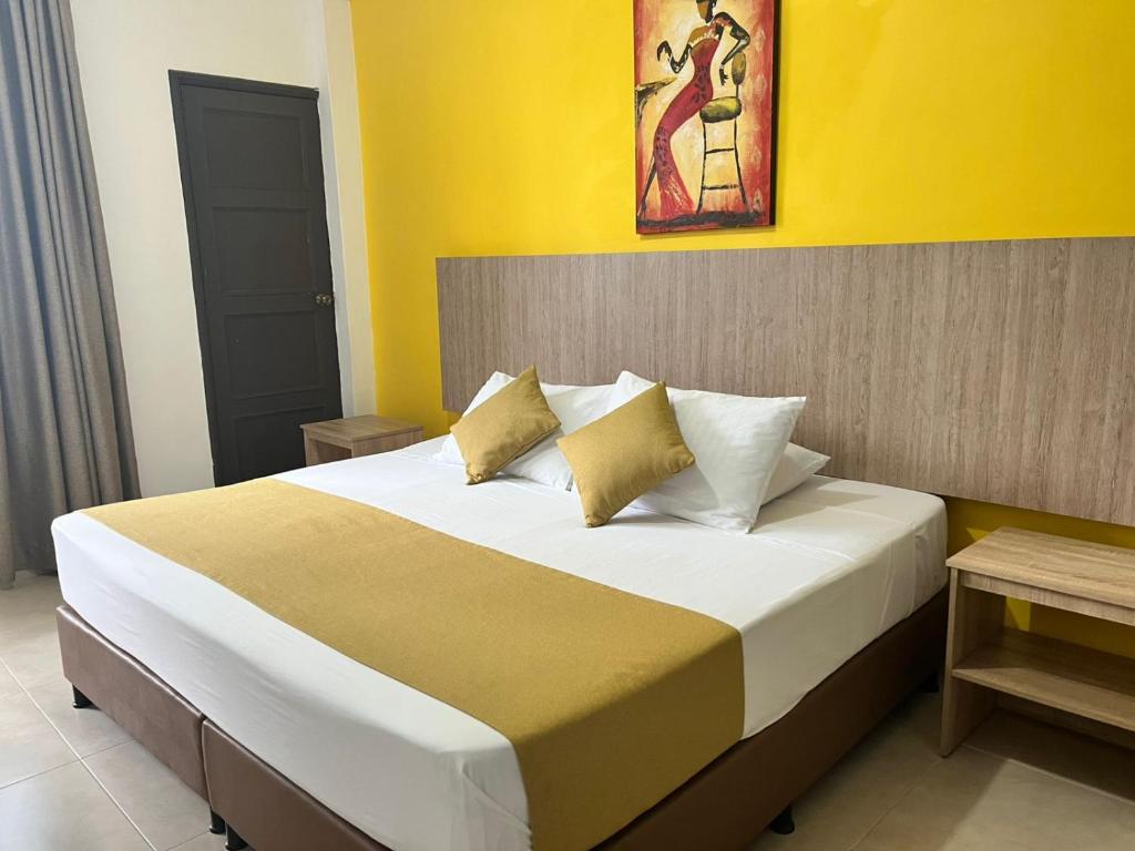a bedroom with a large bed with yellow walls at HOTEL CATALUÑA PEREIRa in Pereira