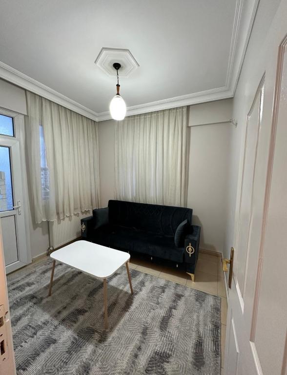 a living room with a black couch and a table at Ozan Konukevi in Hatay